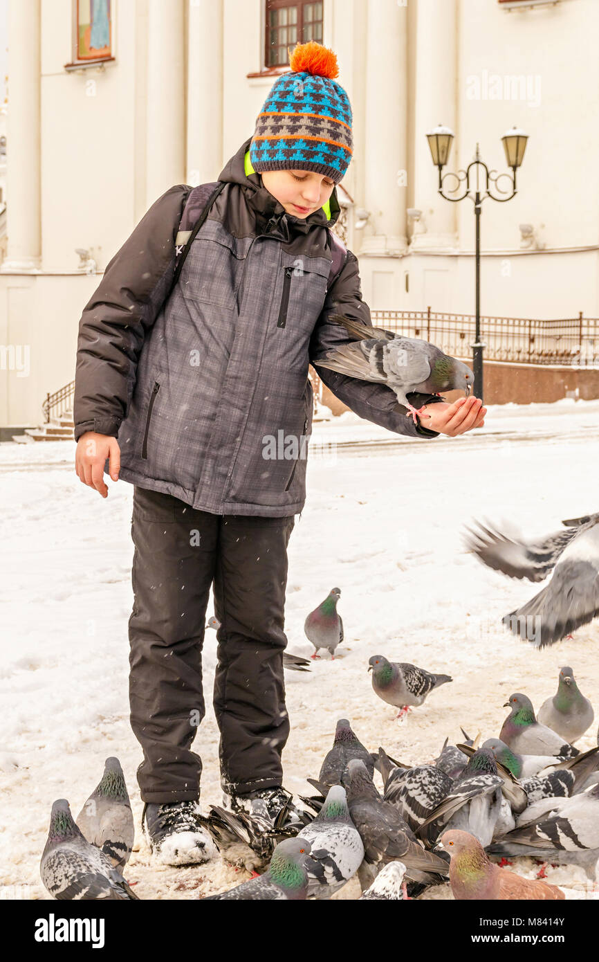 Die Jungen füttert die Tauben auf seine Hände, stehend auf dem Platz vor der Kathedrale Stockfoto