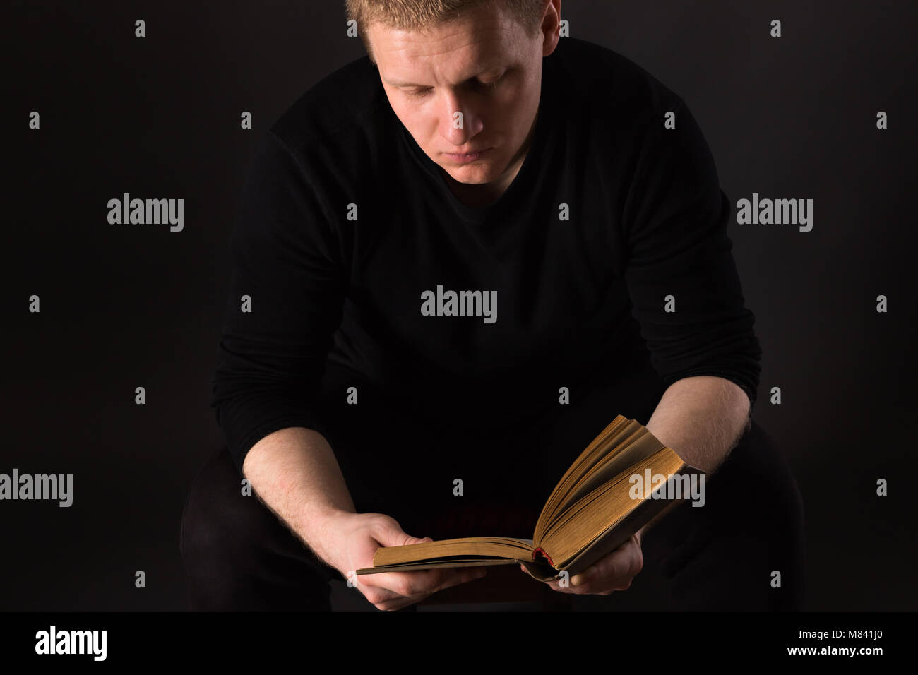 Der Mensch allein, das Buch zu lesen, im Dunkeln bei schwacher Beleuchtung Stockfoto