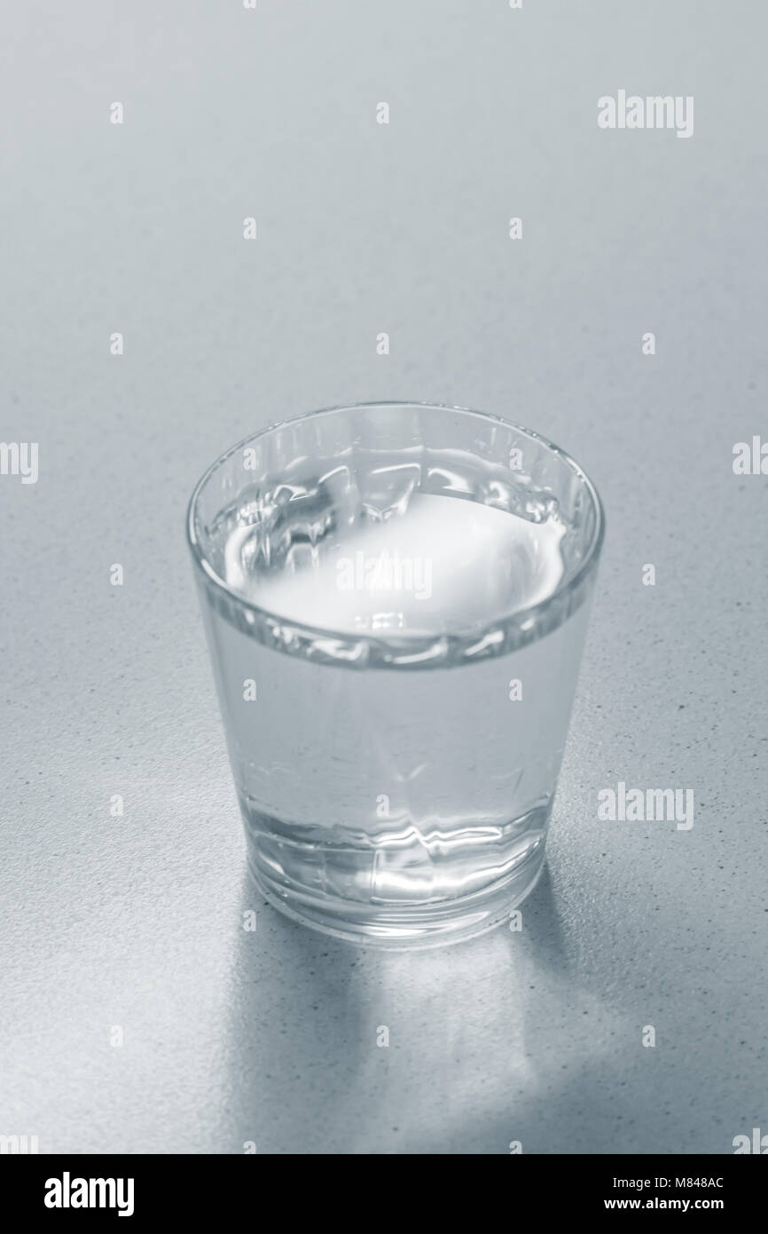 Glas mit einer durchsichtigen Flüssigkeit auf einem Marmortisch Stockfotografie Alamy