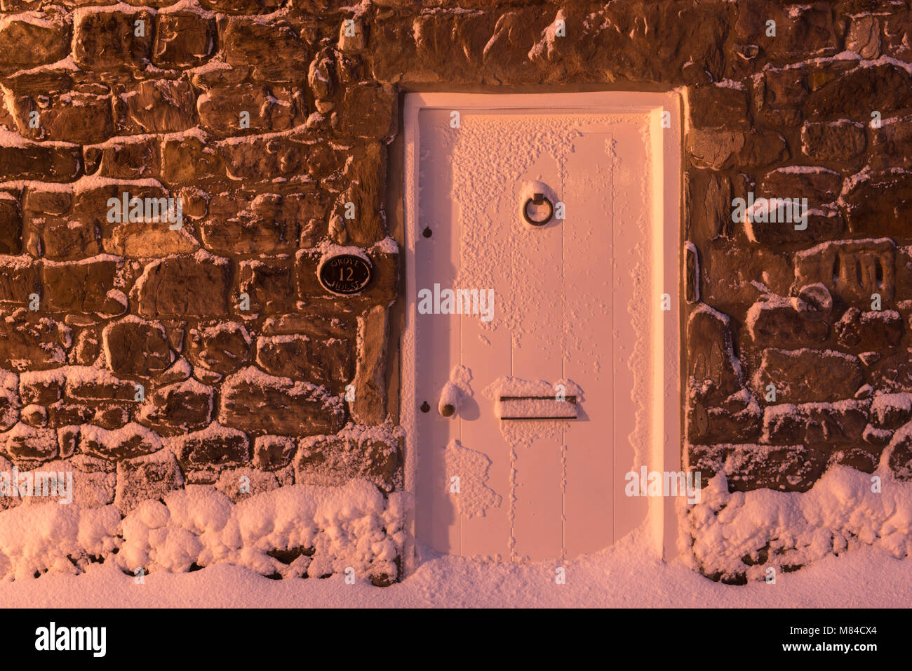 Vordere Tür des Ferienhaus aus Stein nach dem Winter Schnee, Bamburgh, Northumberland, England. Winter (Februar) 2018. Stockfoto