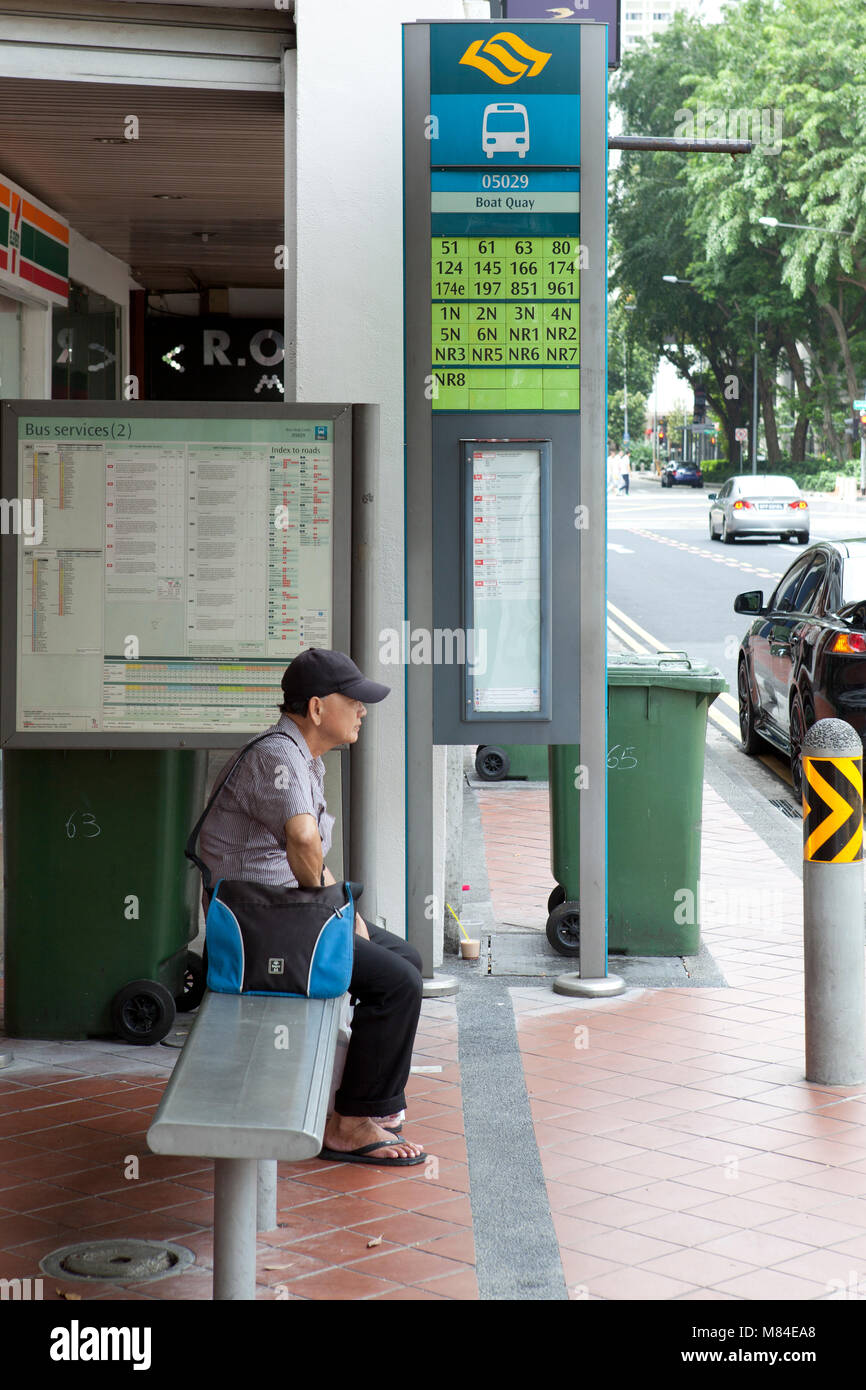 Mann mit Hut an der Haltestelle in Singapur wartet mit Tasche und Hut Stockfoto