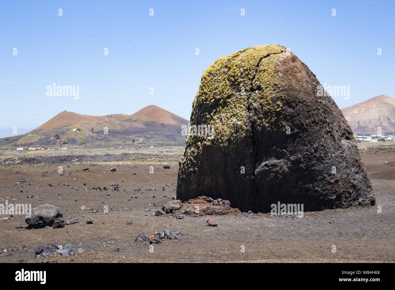 Sehr grosse vulkanische Bombe auf Lanzarote, mit vulkanischen Kegeln im Hintergrund Stockfoto
