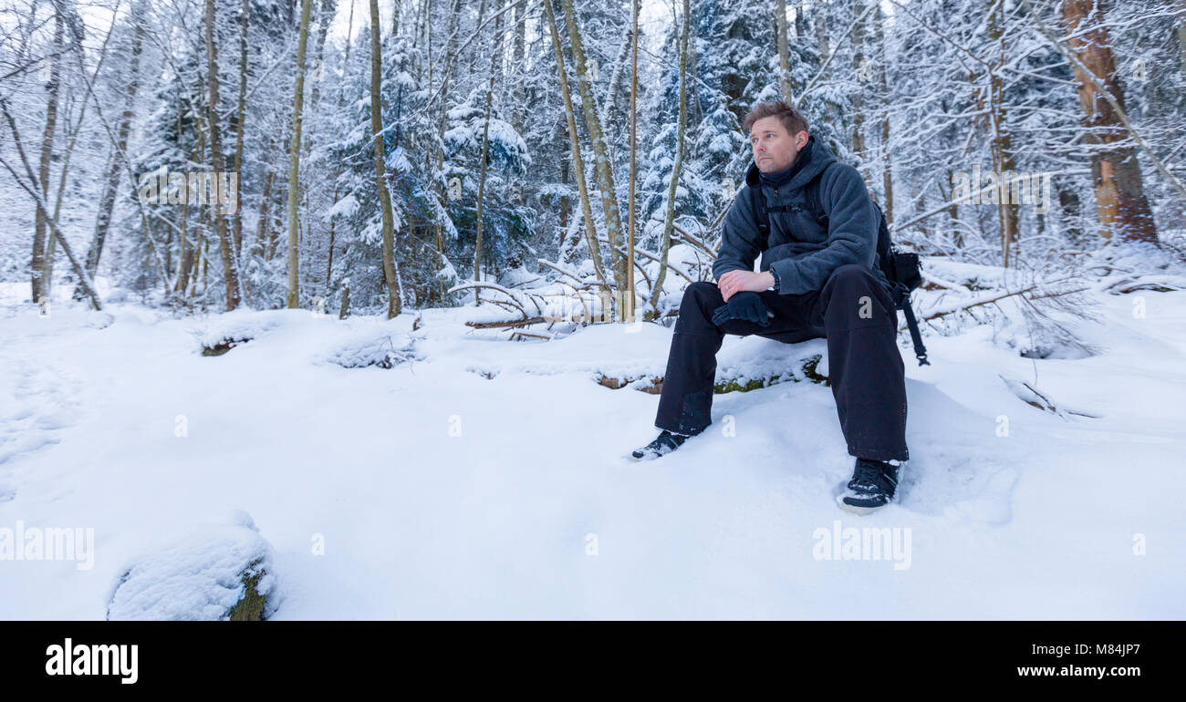 Erwachsene männliche Menschen sitzen im Wald weg schauen in die Ferne Denken in einer Winterlandschaft Model Release: Ja. Property Release: Nein. Stockfoto