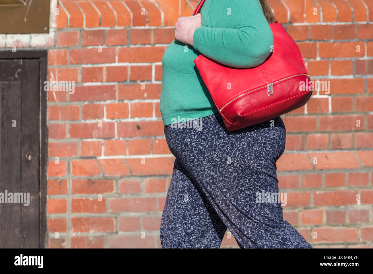 Große beleibte Frau die Handtasche wandern, Seite Profil anzuzeigen, in Großbritannien. Die übergewichtigkeit. Übergewichtige Frauen. Stockfoto