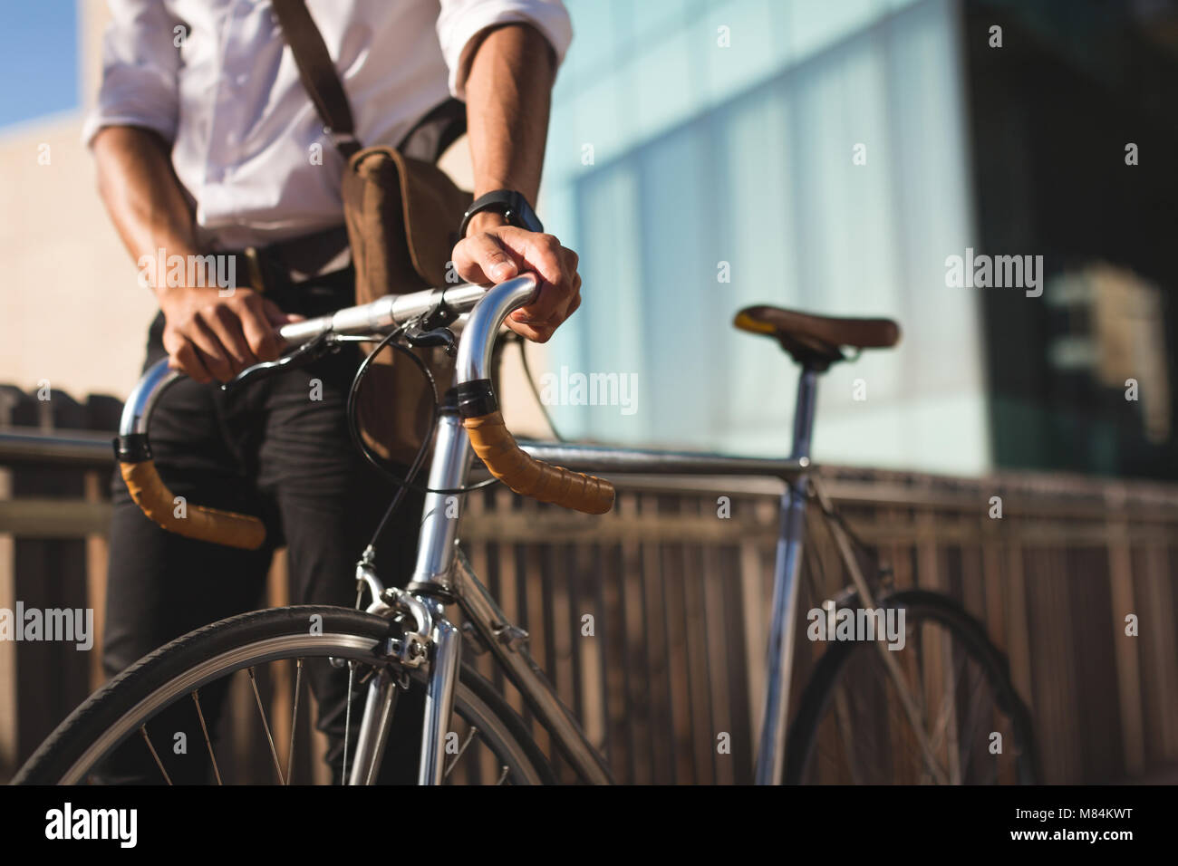 Geschäftsmann mit seinem Fahrrad an Büroflächen Stockfoto