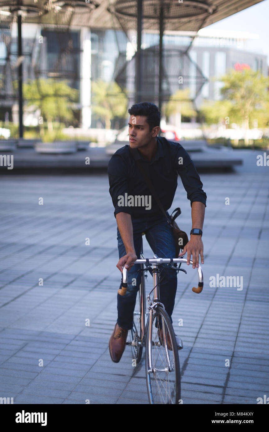 Geschäftsmann auf einem Fahrrad in Büroräumen Stockfoto