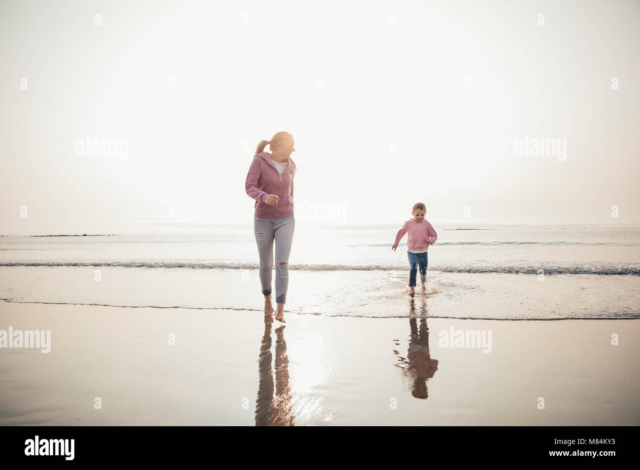 Weitwinkelaufnahme der Mutter und ihrer Tochter, die von der Flut am Strand zu kommen. Stockfoto