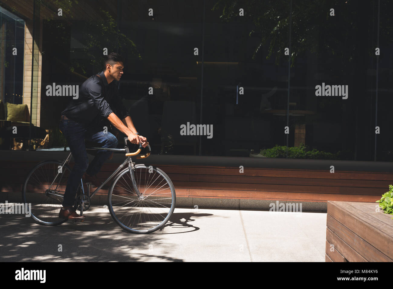 Geschäftsmann auf einem Fahrrad in Büroräumen Stockfoto