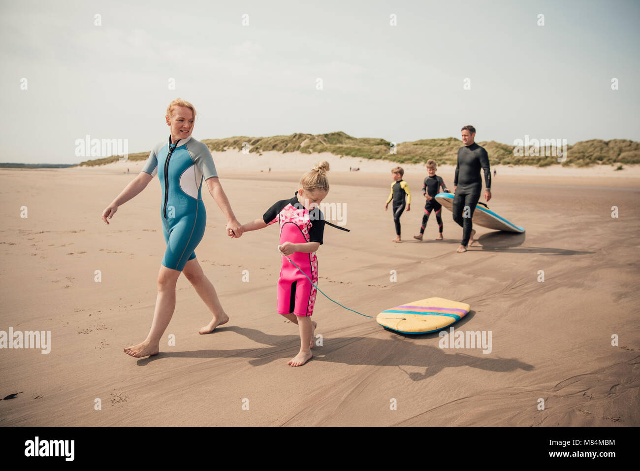 Familie zu Fuß zum Wasser Surfen im Urlaub am Strand zu gehen. Stockfoto