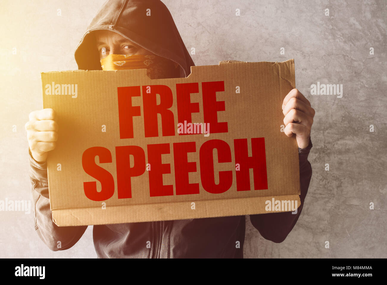 Hooded Aktivist Demonstrant holding Freie Rede Protest anmelden. Mann mit Kapuze und Schal über Gesicht in Aktivismus und kämpfen für die Ursache. Stockfoto