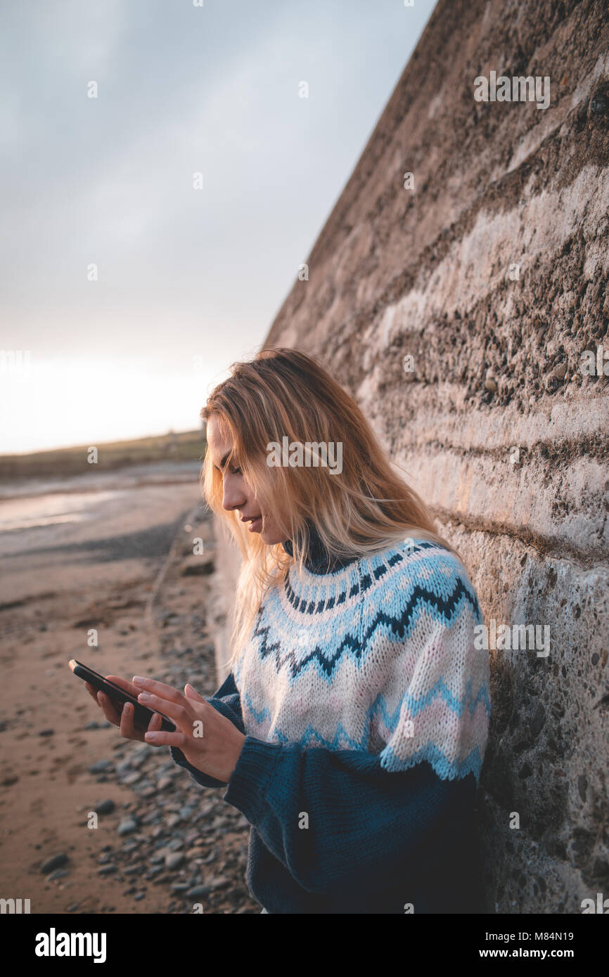 Eine Frau mit Handy am Strand Stockfoto