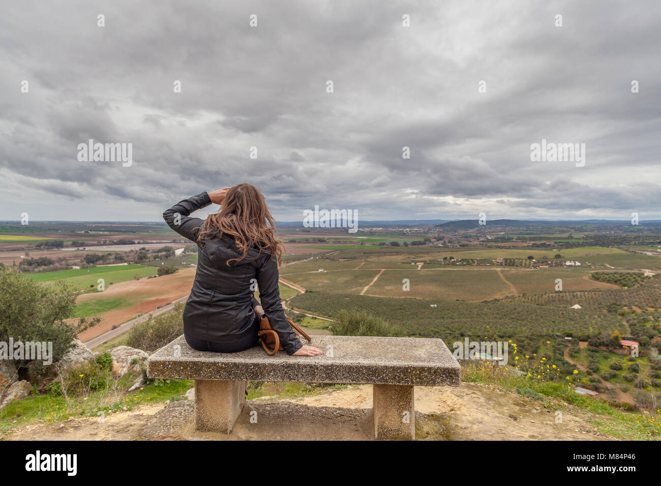 Junge Frau auf Steinbank mit Blick auf Spanisch Plains an bewölkten Tag Stockfoto