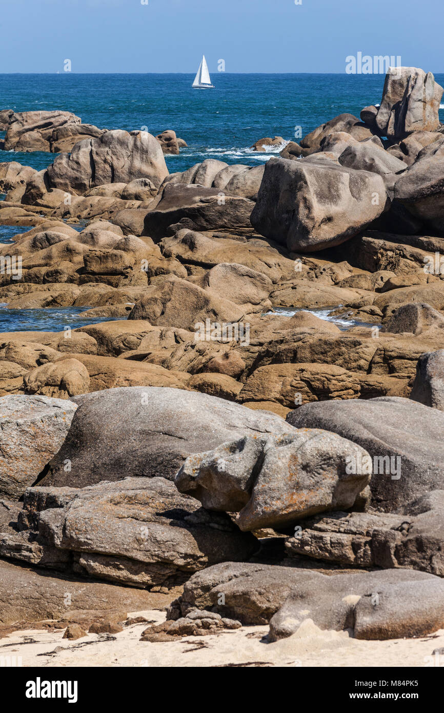 Einzelne weiße Segelboot auf offenen Gewässern und an der Küste Felsen. Stockfoto