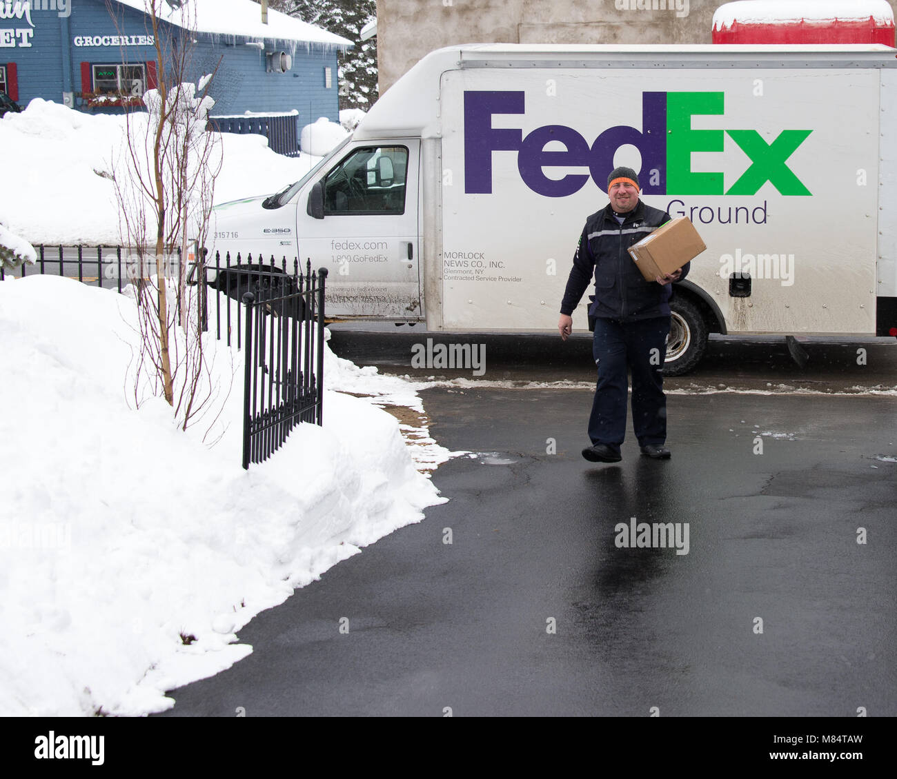 Eine Lieferung von Federal Express liefert ein Paket im Schnee in Spekulant, NY, USA Stockfoto