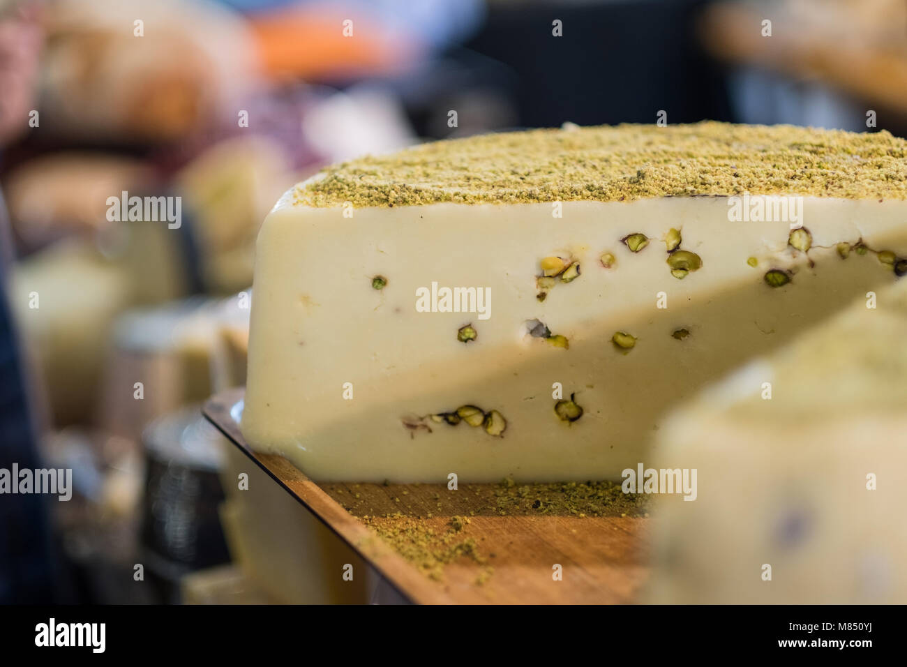 Käse Rad mit Pistazien auf Holz Tablett im Feinkostgeschäft Stockfoto