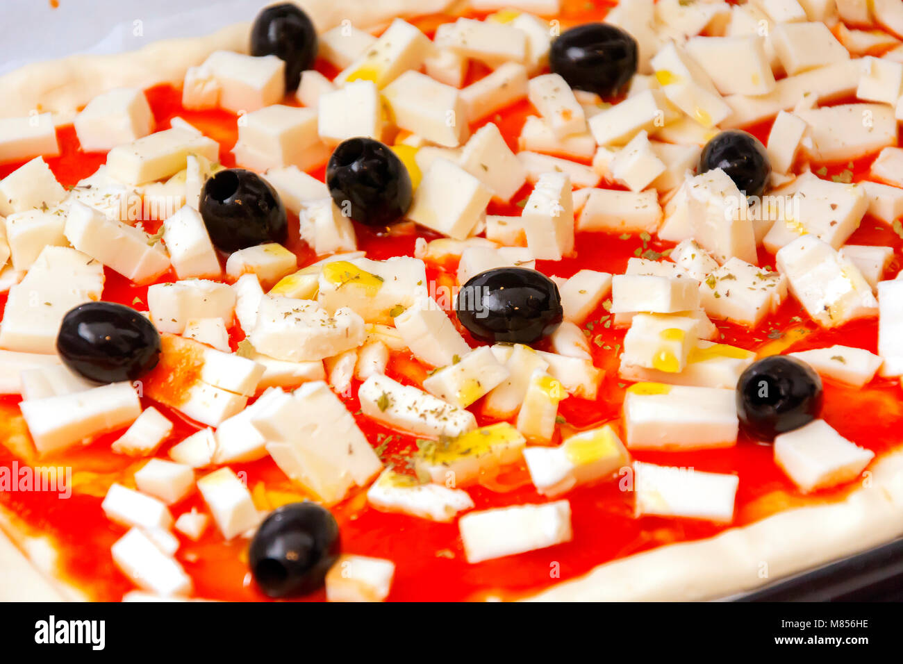Rohe pizza dekoriert Mozzarella, schwarzen Oliven und Tomatensauce fertig gebacken werden Stockfoto
