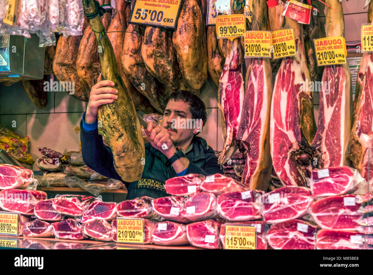 Lebensmittelhändler während spanischer Schinken schneiden am Markt La Boqueria, Barcelona, Katalonien, Spanien Stockfoto
