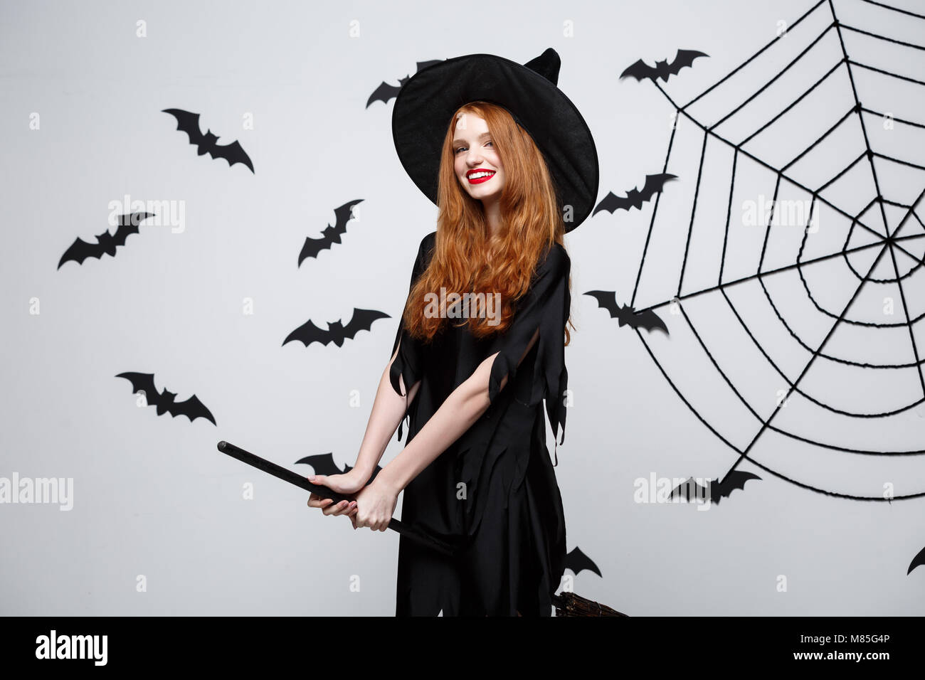 Halloween Konzept - Happy Elegant Hexe mit Besen spielen. Stockfoto