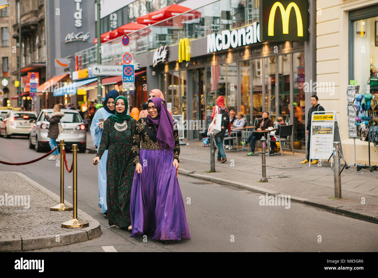 Gruppe von positiven Frauen - die arabischen Flüchtlinge in Trachten mit einem teuren Handy zu Fuß durch die Straßen von Berlin Stockfoto