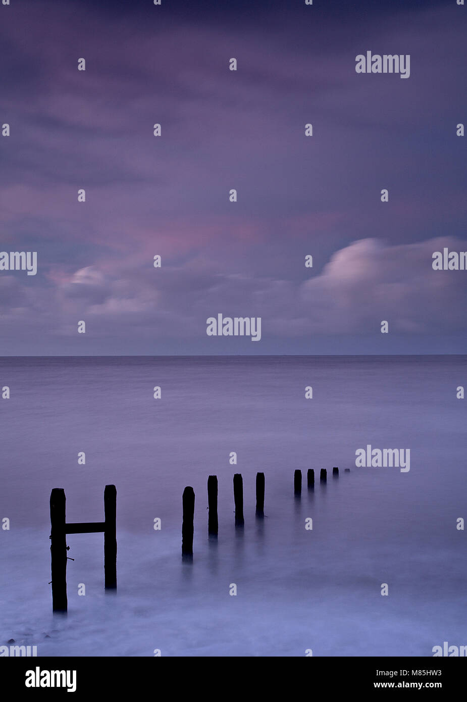 Holz- buhnen im Meer in der Dämmerung, Llandulas, North Wales Küste Stockfoto