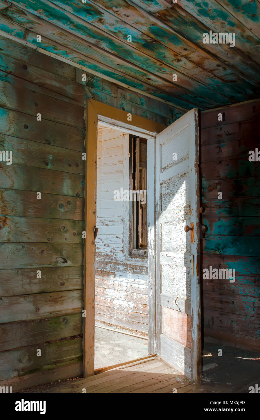 Offener Eingang, alt, abblätternde Farbe, eine hölzerne Eingangstür zum Haus, Boden und Wände im Inneren, ein Fenster ohne Brille, scharfe Schatten von Stockfoto