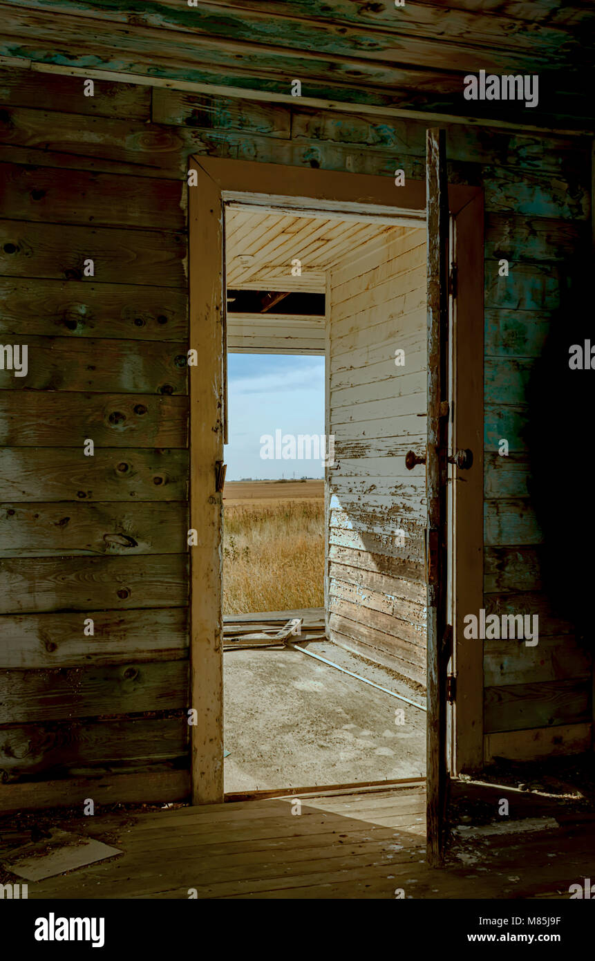 Offener Eingang, alt, abblätternde Farbe, eine hölzerne Eingangstür zum Haus, Boden und Wände im Inneren, ein Fenster ohne Brille, scharfe Schatten von Stockfoto