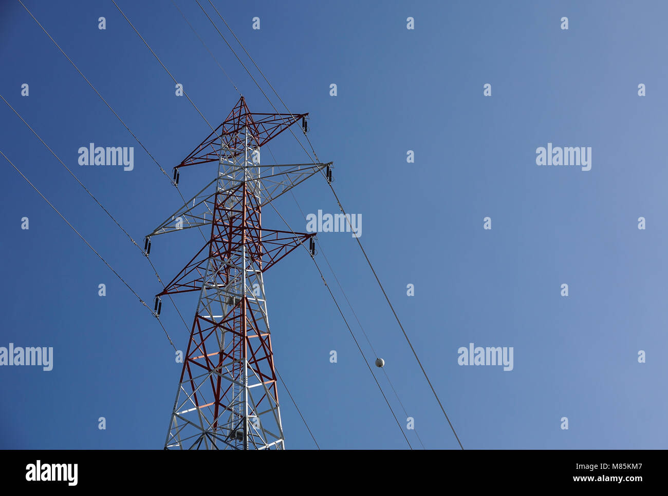 Hohen Hochspannungsleitungen schneiden sich an ein großes Metall Strommast in Maine vor blauem Himmel. Stockfoto