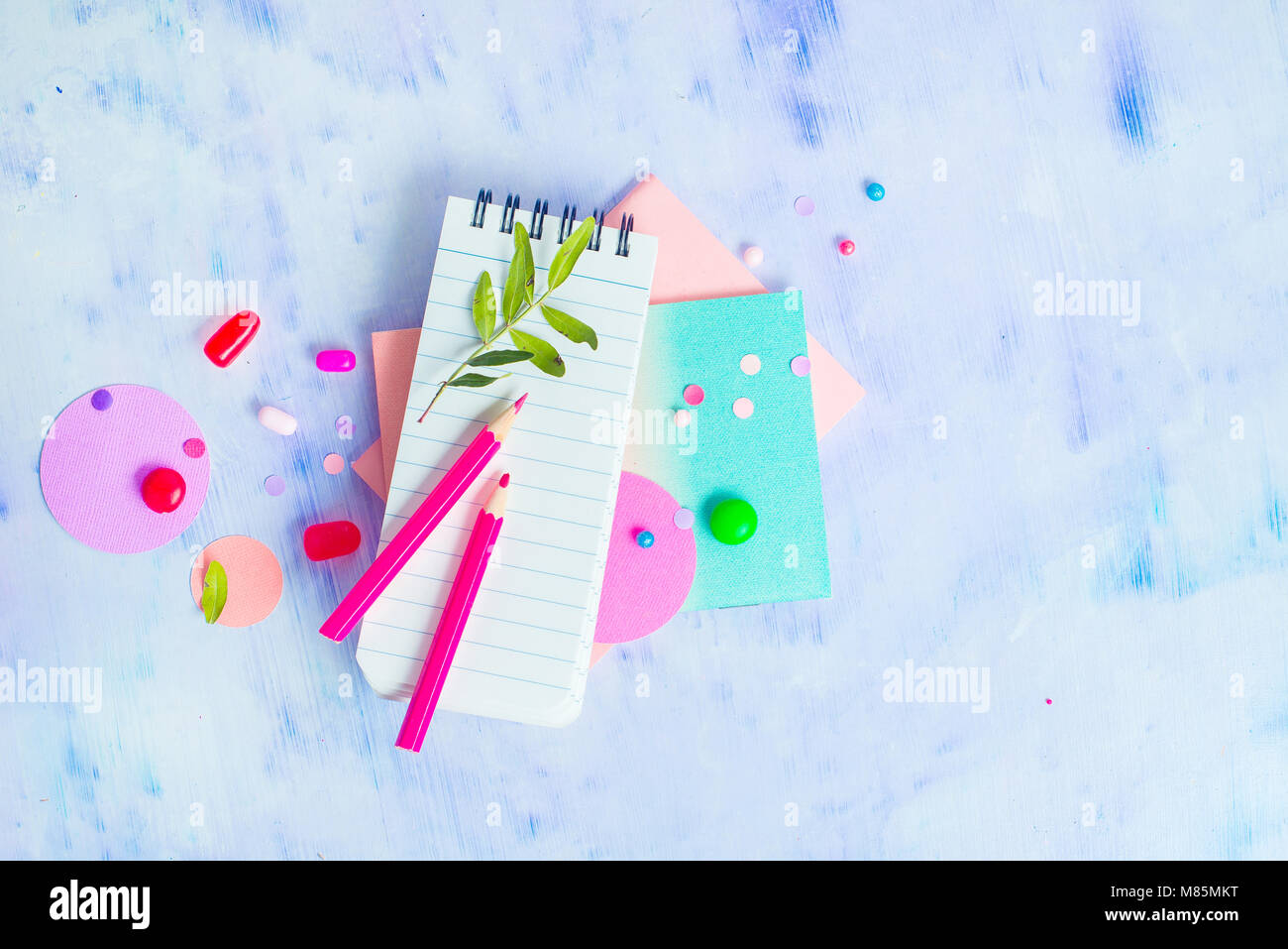 Liniert Notizblock mit bunten Stiften, Süßigkeiten und Rosa macaron Cookie auf einen hellen Hintergrund mit kopieren. Party Planung Spaß Konzept. Schreibwaren Clos Stockfoto