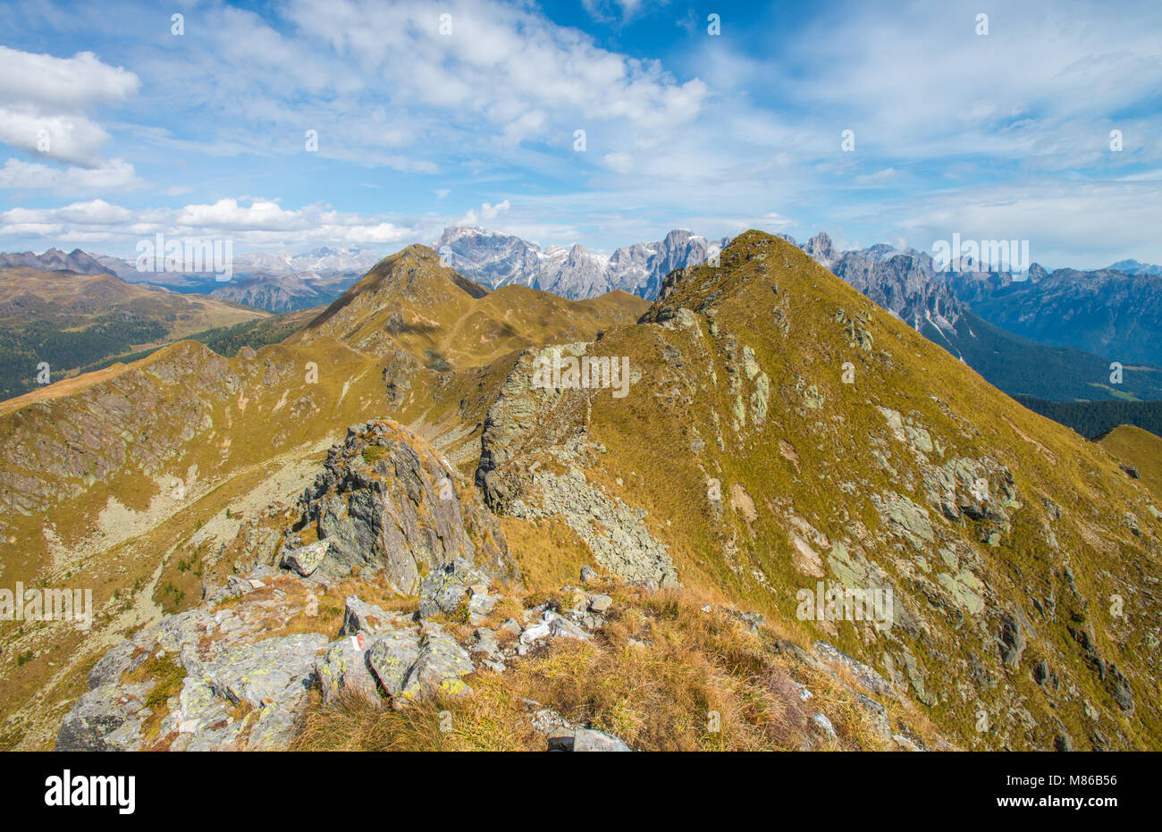 Zwei grasbewachsenen Gipfel Rahmen weit entfernte Bergkette der Pale di San Martino, Italien, italienische Alpen. Felsen, Sommer Wanderweg, Wolken und weiten Landschaft. Stockfoto