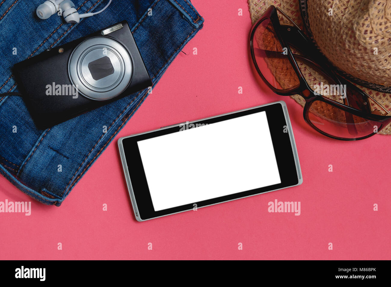 Smartphone, Kleidung, Sonnenbrille, Fotoapparat, braunen Hut, auf Rosa Hintergrund. Ansicht von oben Travel Concept Mock up. Stockfoto