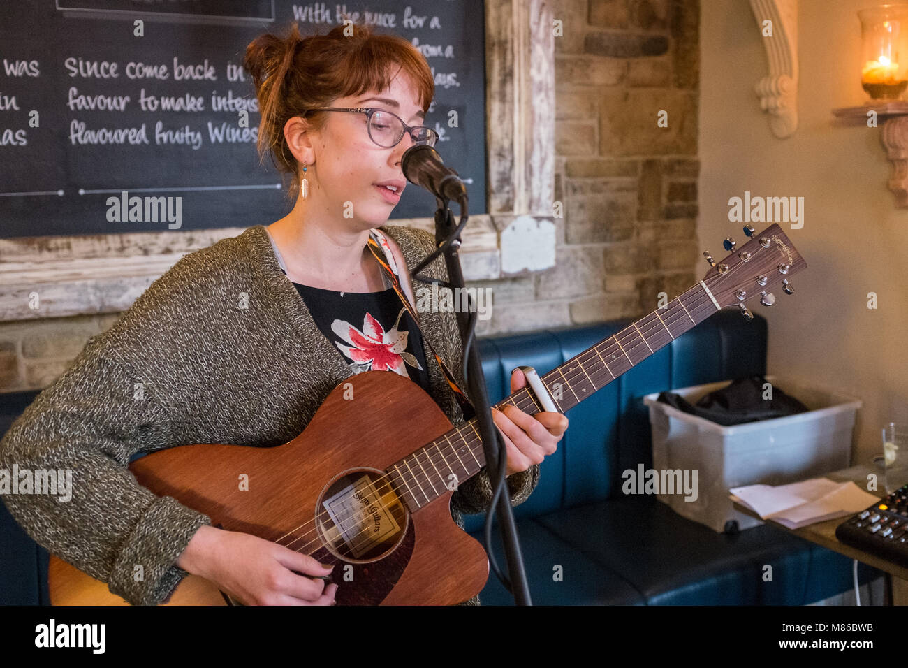 Weibliche Musiker spielen akustische Gitarre Gesang leben in einer Bar. Stockfoto