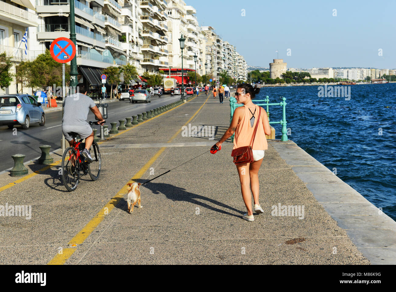 Eine Griechin, die auf der Uferpromenade mit dem Weißen Turm von Thessaloniki im Hintergrund läuft. Stockfoto