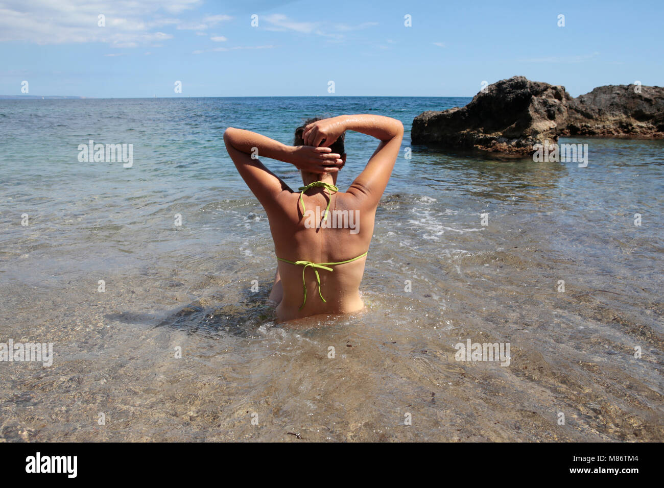 Frau, die im Meer steht und ihr Haar hält, Punta Negra, Mallorca, Spanien Stockfoto