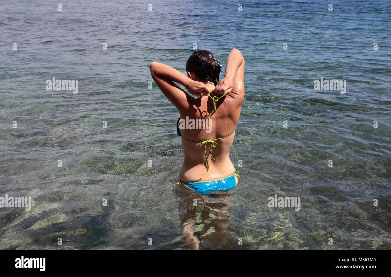 Frau im Meer stehend, die ihr Bikini-Top bindet, Punta Negra, Mallorca, Spanien Stockfoto
