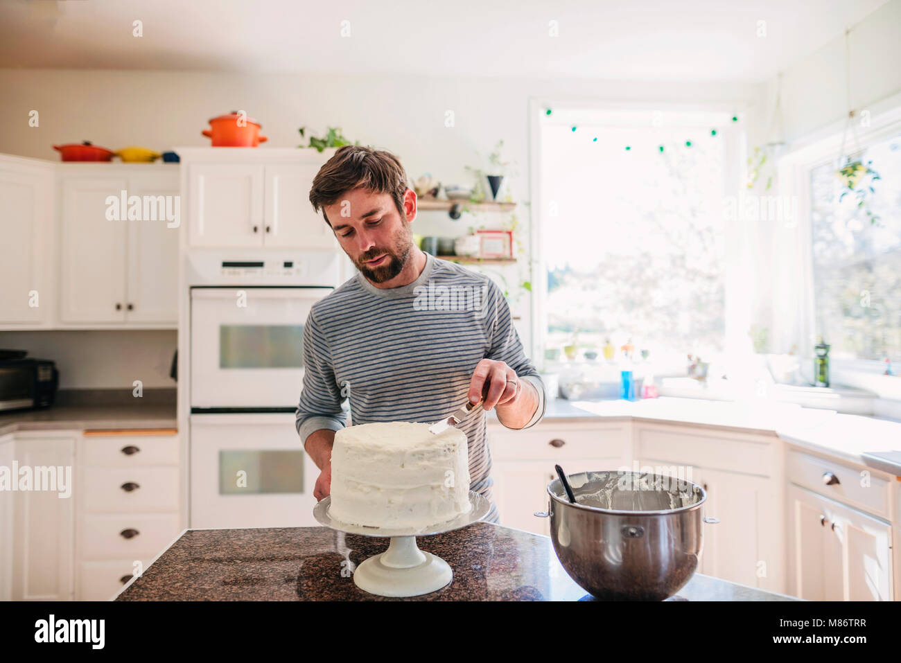 Mann in der Küche einen Kuchen dekorieren Stockfoto