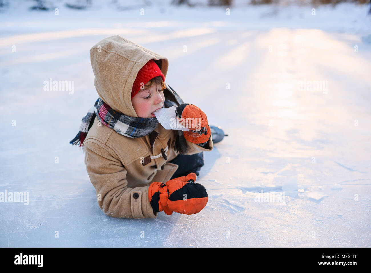 Junge lag auf einem zugefrorenen See mit Schlittschuhen Eis essen Stockfoto