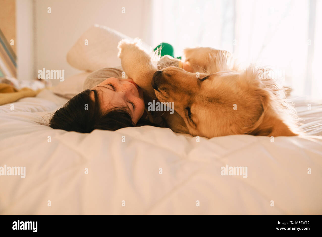 Mädchen liegt auf einem Bett mit ihrem Golden Retriever Hund Stockfoto