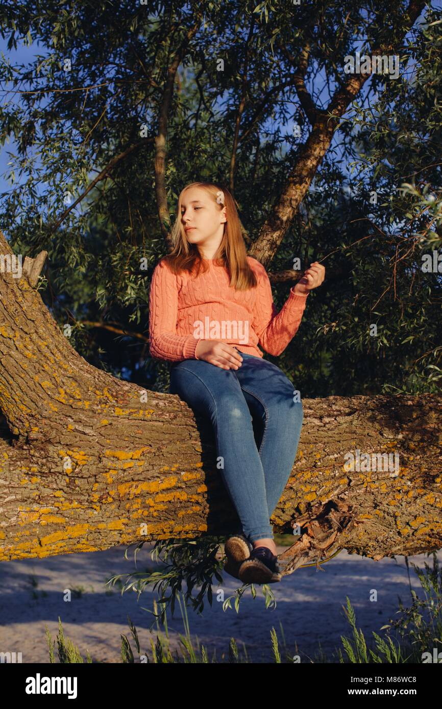 Mädchen sitzen auf einem Baumstamm Stockfoto