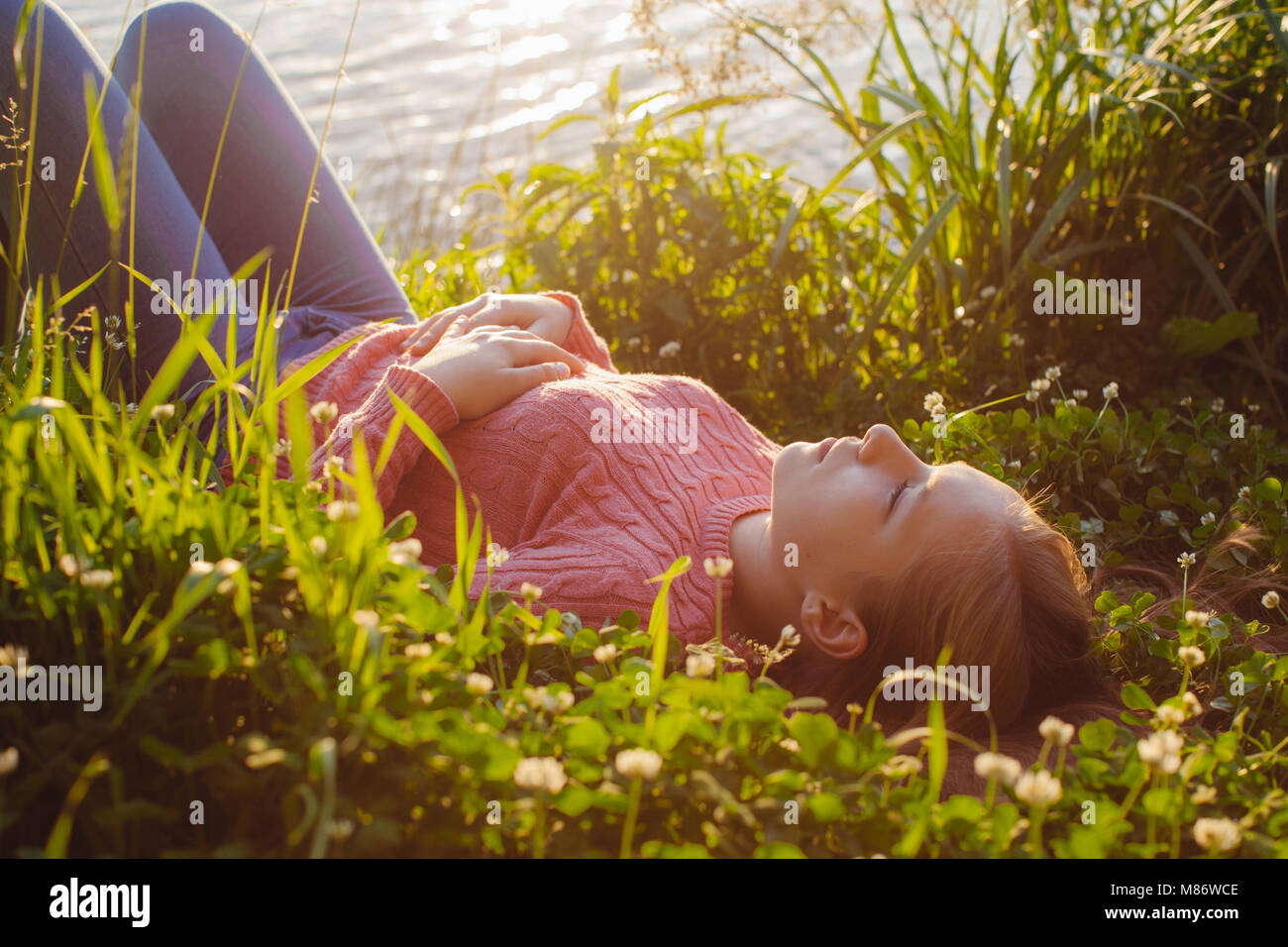 Mädchen liegt auf Gras an einem See Stockfoto
