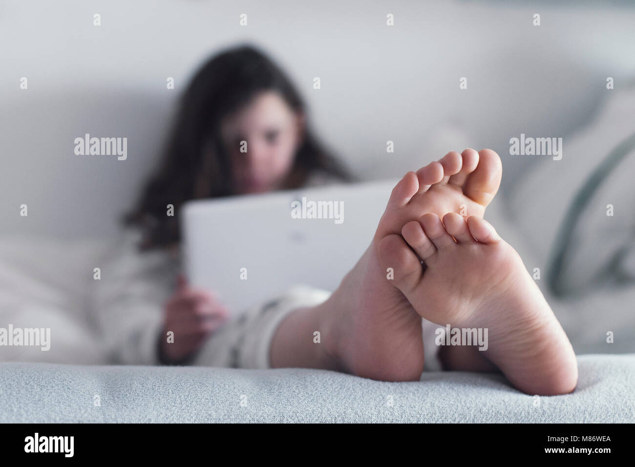 Mädchen im Bett sitzen mit einem digitalen Tablet Stockfoto