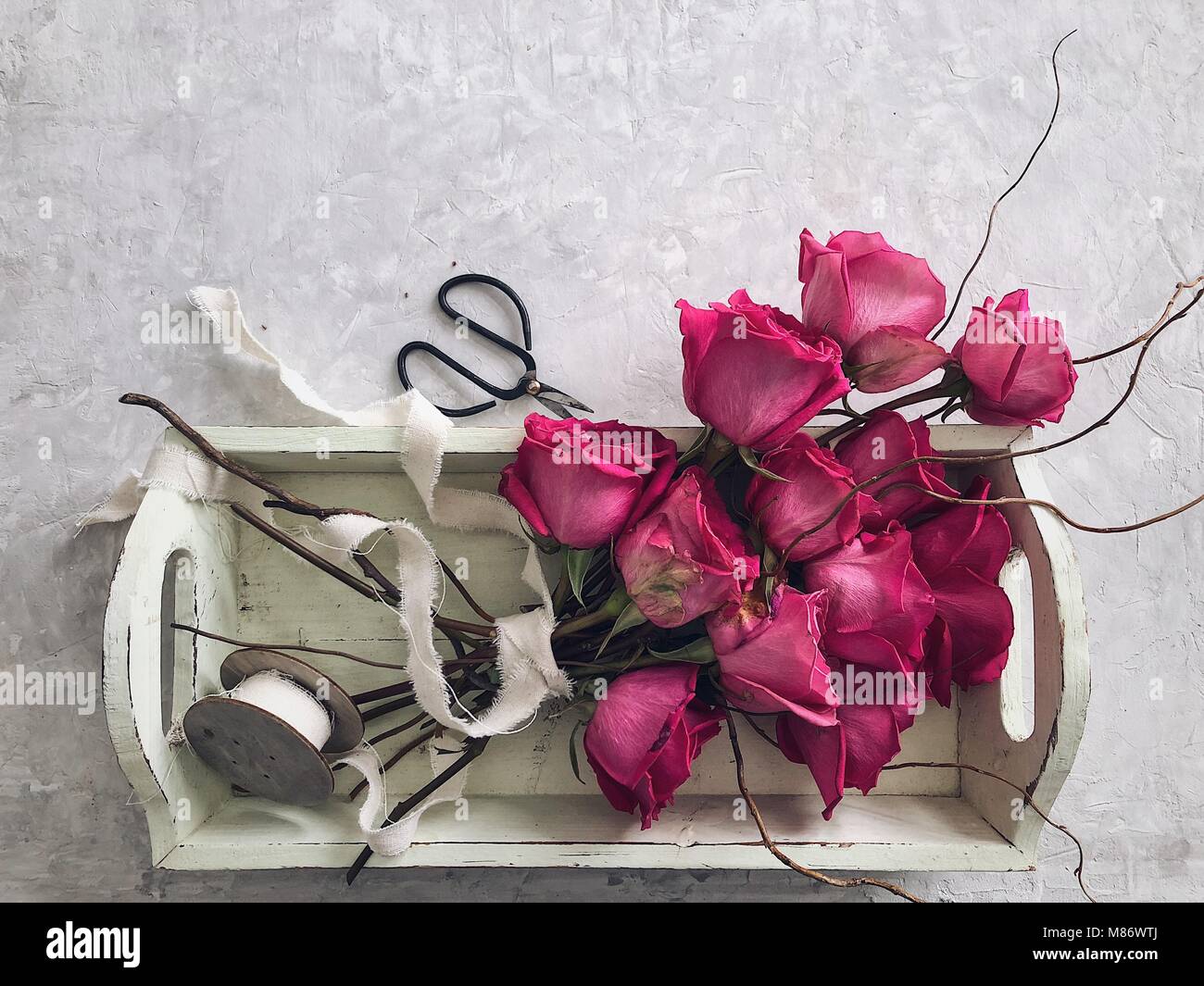 Blumenstrauß aus Rosen auf einem Tablett mit Band und Schere Stockfoto