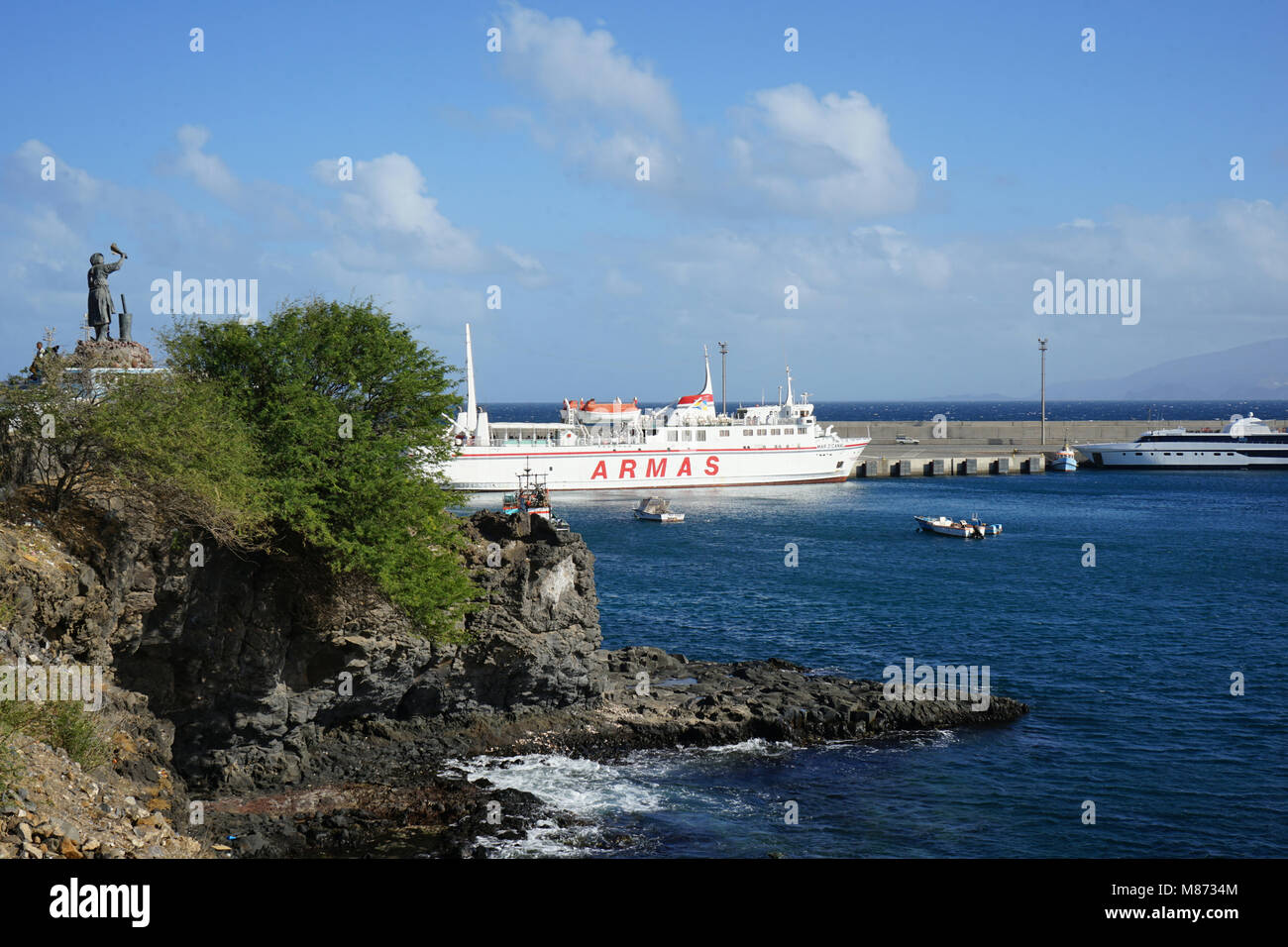 Menschliche Migration Denkmal, Winkende Frau, Fähren und Fischerboote im Hafen von Porto Novo, Santo Antao, Kap Verde Stockfoto