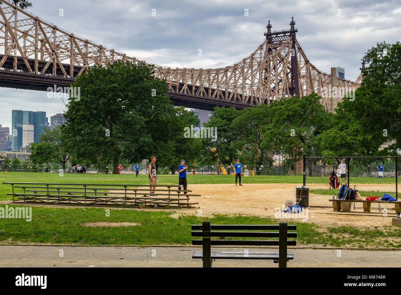 Baseballspieler im Queensbridge Park, einem Stadtpark unterhalb der 59th St Queensboro Bridge, Long Island City, Queens, New York, USA Stockfoto