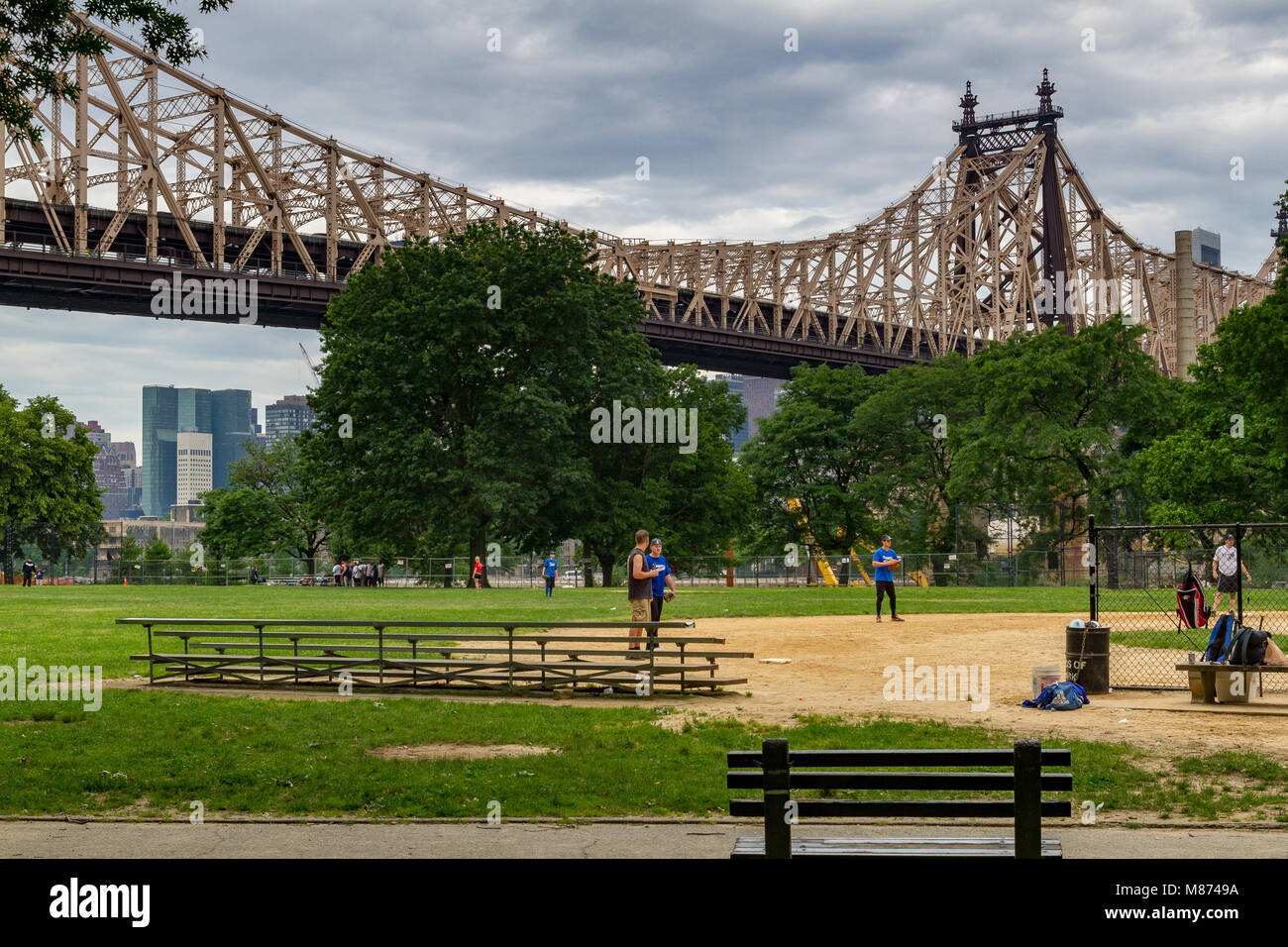 Baseballspieler im Queensbridge Park, einem Stadtpark unterhalb der 59th St Queensboro Bridge, Long Island City, Queens, New York, NY, USA Stockfoto