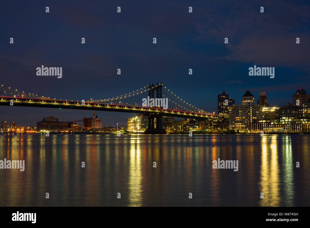 Die Manhattan Bridge und Brooklyn leuchtet in der Dämmerung mit den Überlegungen in den East River, New York, USA Stockfoto