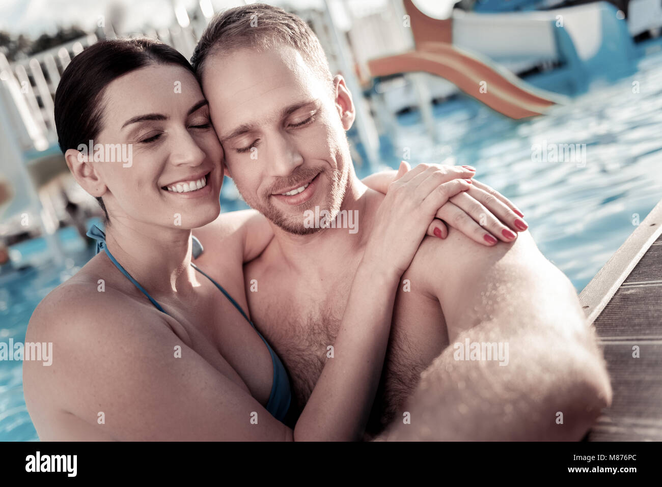 Fröhliche junge Frau und Mann genießen die Zeit zusammen im Pool Stockfoto