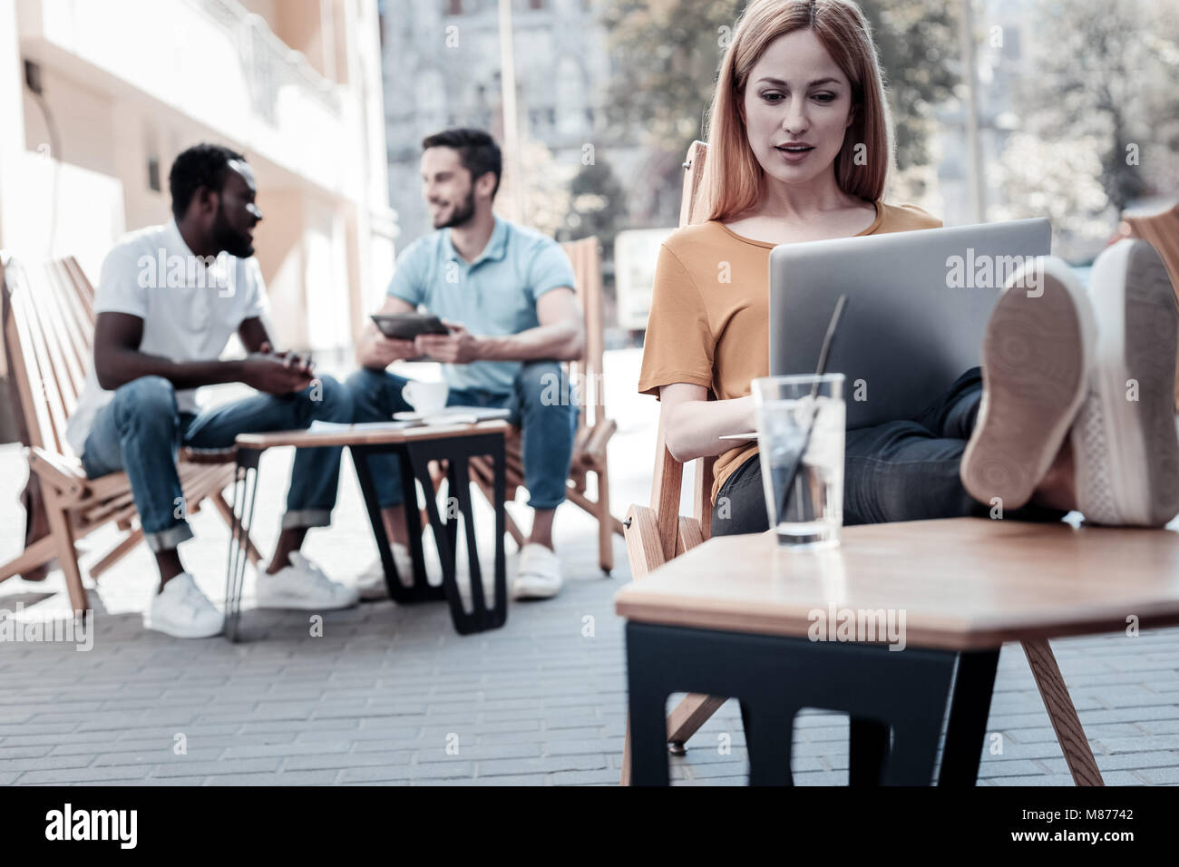 Begeisterte junge Dame Arbeiten am Laptop im Freien Stockfoto