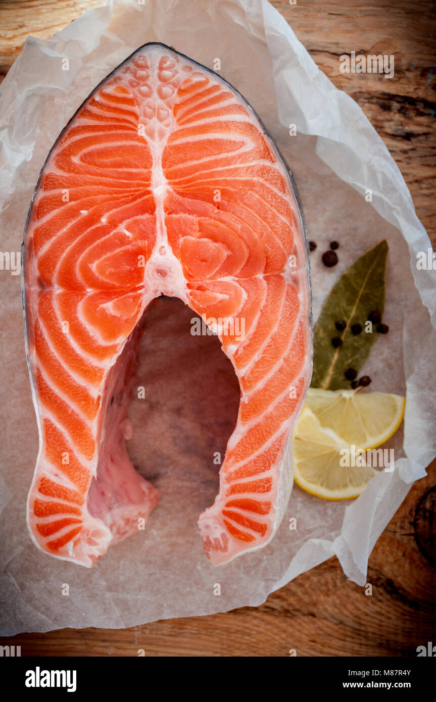 Roher Lachs Fisch Steak mit Zitrone und Gewürzen auf Holz- rustikalen Hintergrund. Frischen Fisch. Ansicht von oben Stockfoto