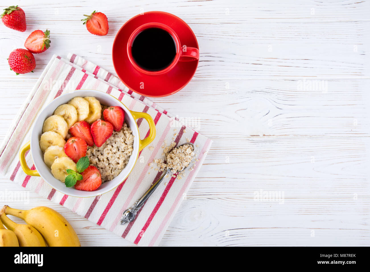 Frühstück Haferflocken Haferbrei mit Früchten, Beeren und Kaffee Tasse. Haferflocken mit Erdbeeren und Bananen. Gesundes Frühstück Konzept. Ansicht von oben Stockfoto