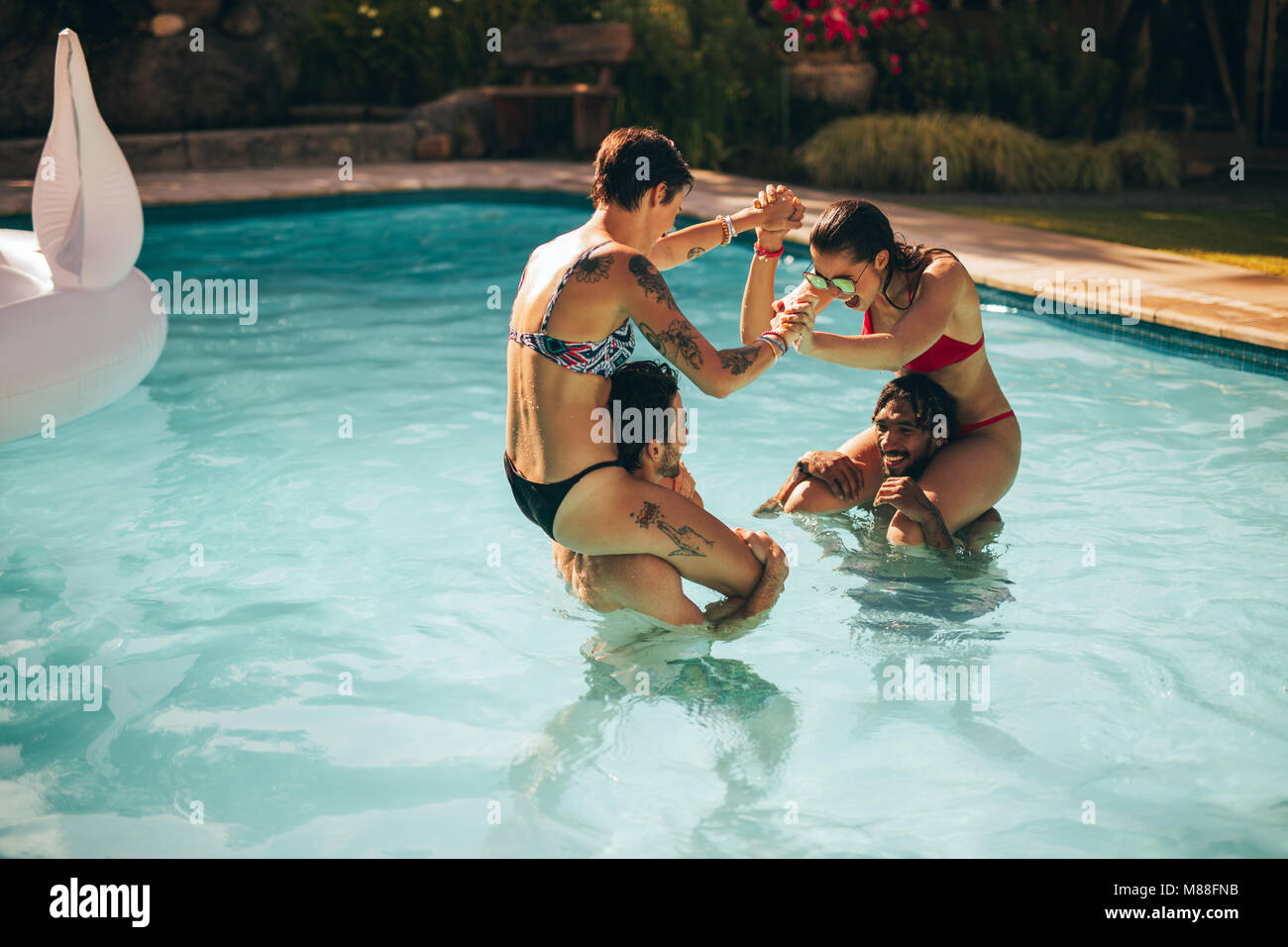 Freunde Spaß im Holiday Resort Pool. Die Mädchen sitzen auf ihre Freunde Schultern und genießen im Pool. Stockfoto